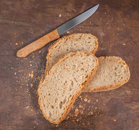 Organic wholegrain bread on dark ructic wooden background with a knife. Fresh bread top view.の写真素材