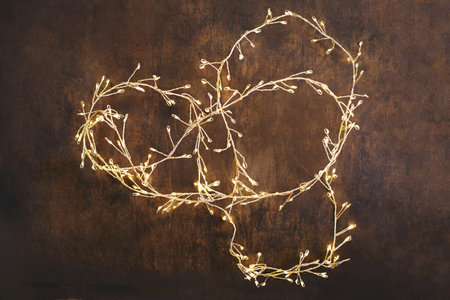 Christmas lights on adark woodeen background. Golden Xmas decorations glowing garland top view, copyspaceの写真素材