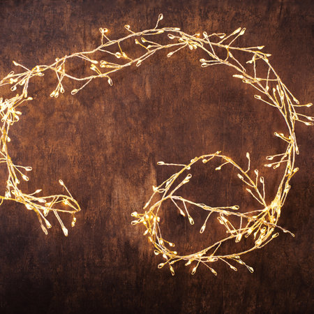 Christmas lights on a brown wood background. Golden Christmas garland top view, copyspaceの写真素材