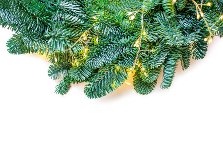 Christmas Tree Border Isolated On White Background. Fir tree branches with sparkling golden lights garland closeup. Xmas, New Year concept.の写真素材
