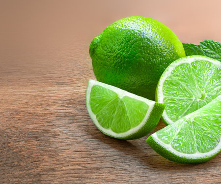 Lime fruit with lime slices on wooden table. Detox diet concept. Fresh lime on a rustic backgroundの写真素材