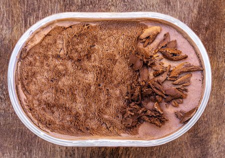 Chocolate icecream on a wooden rustic background. Dark chocolate ice cream in a containerの写真素材