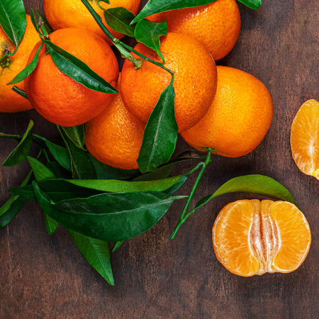 Fresh mandarin oranges fruit or tangerines with leaves on rustic wooden table, top view. Flat layの写真素材