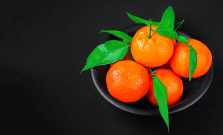 Fresh mandarin oranges fruit or tangerines with leaves on black background. Copyspace. Fresh picked mandarins Top view.の写真素材