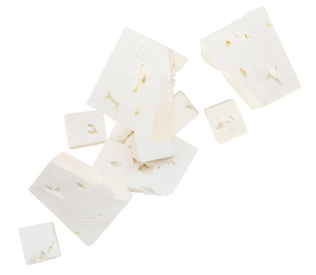 Falling Feta cheese isolated on white. Explosion of Greek fitaki cheese pieces. Flying Fresh soft cheese. Creative layoutの写真素材