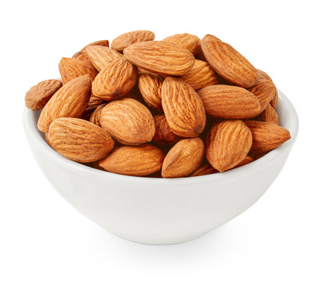 Heap of Almonds in a white bowl isolated on white background. Sweet Almond nut seeds pile.の写真素材