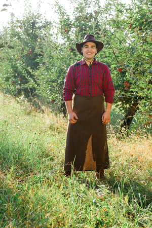 Young happy man in the garden collect ripe apples.の写真素材