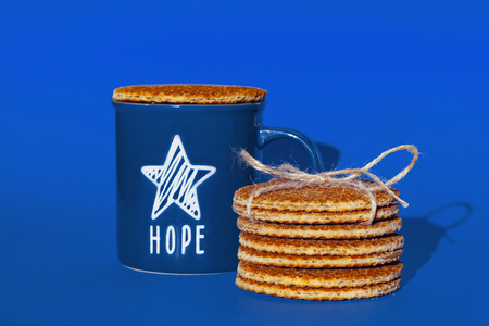 Dutch waffle called a stroopwafel on a blue background with blue cup of tea or coffee.の写真素材
