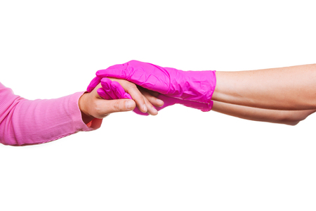 Female hands of a nurse or doctor in pink medical gloves hold hands of an old woman. Concept of care and support in hospice.の写真素材