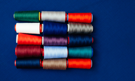 A set of threads of different colors on the blue backgtound. Many threads for sewing and needlework are different in color and size. Multicolored palette of threads.の写真素材
