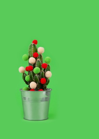 Funny holiday cactus tree with colored balls. Green tropical flower us a gift for celebration or party on the green background.の写真素材