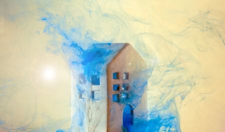 Small ceramic house under the water with violet acrylic paints. Fabulouse white ceramic house at the night with smoke from windows and doors.の写真素材