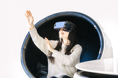 Young girl with headset on hir face gets acquainted with new technologies. Woman using the virtual reality headset.の写真素材