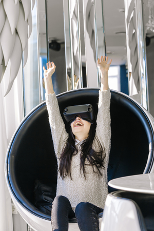 Young girl with headset on hir face gets acquainted with new technologies. Woman using the virtual reality headset.の写真素材