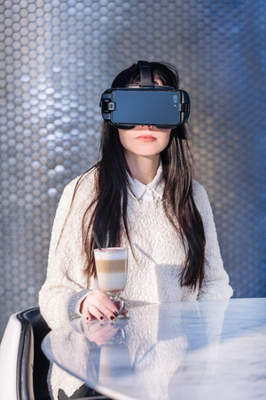 A young girl with a headset on the face meets new technologies. Woman using virtual reality headset.の写真素材