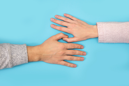 Women's hand goes to the man's hand on blue background.の写真素材