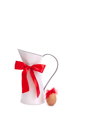 White milk jug with red bow and funny egg on the white background. Valentine's day or woman greeting card.の写真素材
