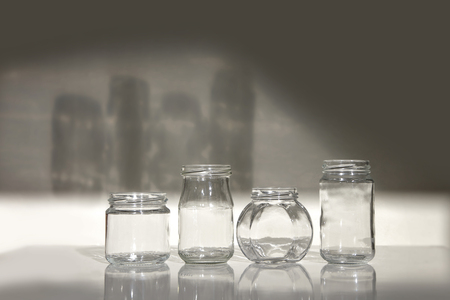 Four clean glass jars on white table with shadow. Set of empty jars isolated on white background.の写真素材