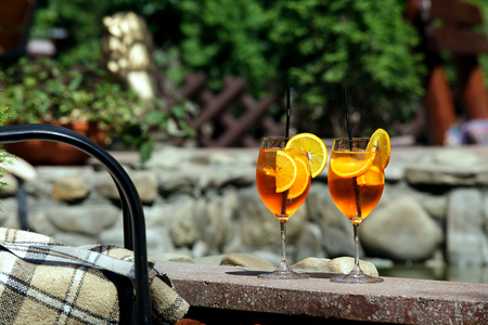 Aperol spritz cocktail in glass on the table against a bright sunny cafeand leaves.の写真素材