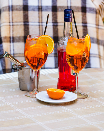 Aperol spritz cocktail in glass and bottle on the wooden table. Two glasses with a cocktail and an ice bucket.の写真素材