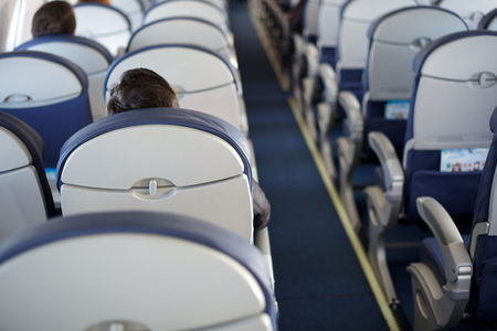 Half-empty airplane with few passengers. Passengers inside the cabin of a commercial airliner during flight.の写真素材