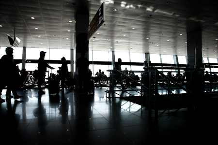 Silhouettes of passengers in a large airport in the background of windows. Passengers waiting at gate terminal in Airport.の写真素材