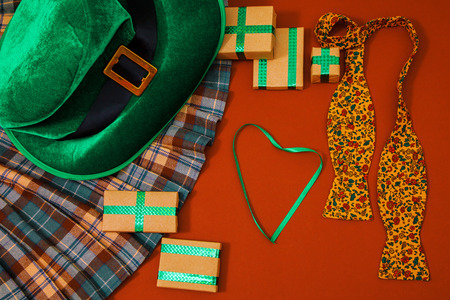 A St. Patrick's day costume hat of a leprechaun. On the orange background there are gifts kilt tie and a green heart.の写真素材
