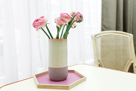 Pink flowers in a lilac vase against a white window. Aster bouquet in the vase on the table.の写真素材