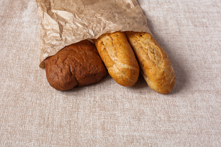 Different bread ciabatta without yeast. Fresh bread in paper on the canvas background. Healthy food concept.の写真素材
