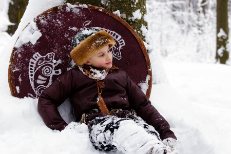 Portrait of a young viking. Viking warrior with chain mail leather spear walking in winter woods before battle, scandinavian traditional clothing for lumberjack, viking concept.の写真素材