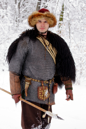 Portrait of a Viking Warrior Man. Viking warrior with chain mail leather spear walking in winter woods before battle, scandinavian traditional clothing for lumberjack, viking concept.の写真素材