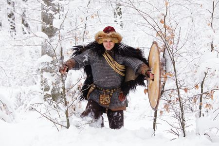 Portrait of a Viking Warrior Man. Viking warrior with chain mail leather spear walking in winter woods before battle, scandinavian traditional clothing for lumberjack, viking concept.の写真素材
