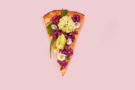 Slice of pizza on a pink background with spring flowers. Piece of pizza with bouquet of lilac, tulip and camomile.の写真素材