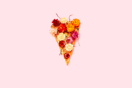 Slice of pizza on a pink background with spring flowers. Piece of pizza with bouquet of lilac and camomile.の写真素材