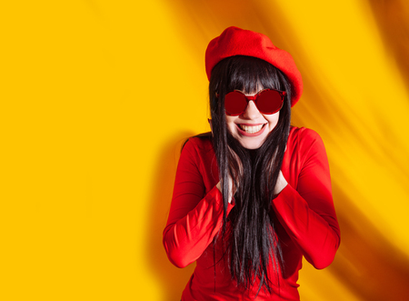 Young woman in red glasses and hat with shadow from tropical leaves. Glamorous brunette on hot yellow background with sun light and shadow.の写真素材