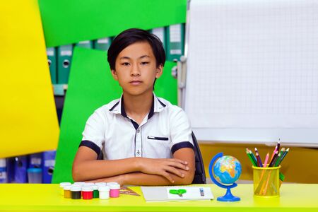 A classman studies in the classroom or library and does homework. Portrait of a schoolboy sitting at table with books.の写真素材