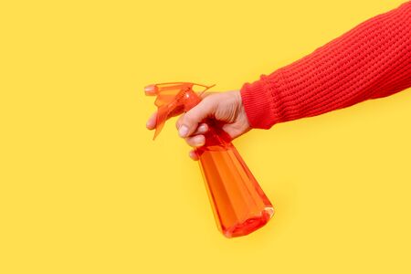 Hand holds red dispenser on the yellow background. Female hand in white glove with sprayer for cleaning.の写真素材