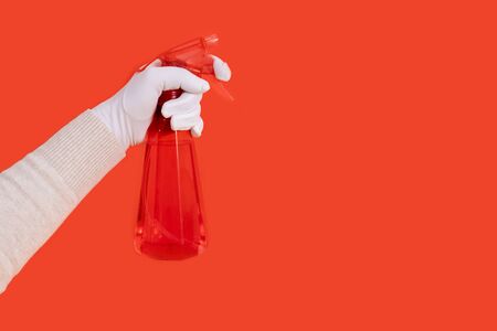 Hand holds red dispenser on the red background. Female hand in white glove with sprayer for cleaning.の写真素材