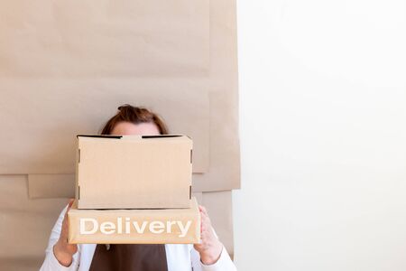Packer's hands holding a Craft Paper Bag and Box. Worker dressed in brown apron Packing Order for Customer.の写真素材