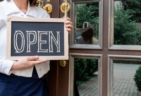 Woman's hands holds dashboard with text open. Worker shows advertising opening of the cafe or restaurant.の写真素材