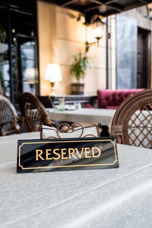 A tag of reservation placed on table. Reserved in a restaurant or summer terrace of cafe.の写真素材