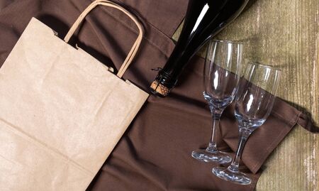 Wine Bottle, Glasses, packing bag and box on the wooden background with brown apron. Concept of Delivery Service for Customer.の写真素材