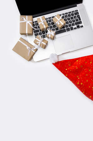Laptop with gifts, red Hat and Packing boxes on the white background, top view, delivery concept.の写真素材