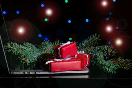 Laptop, Red Gift's Boxes and Christmas Tree on the black background with lights.の写真素材