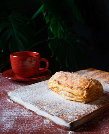 Fresh Puff on the table with a red cup of coffee on the black background.の写真素材