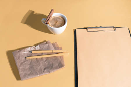Notepad with a cup of tea on the pastel orange tableの写真素材