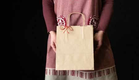 Woman dressed in red festive apron holding Shopping Bag on the eve of New Year.の写真素材