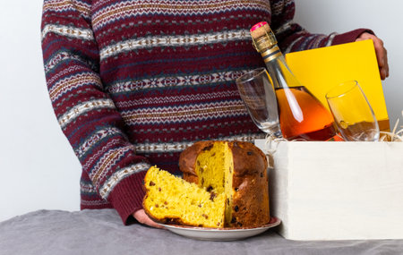 Female hand holding easter panetone italian piece near delivery box with champagne bottle.の写真素材