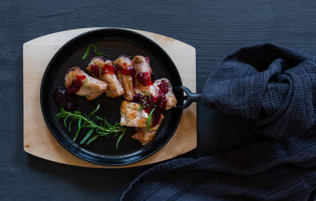 Cast-iron black round pan with fried pork on the black or blue background, top view.の写真素材
