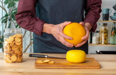 Hands of man hold whole holland cheese Edam and dutch goat cheese from Netherlands on the kitchenの写真素材